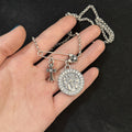 Chrome Hearts brooch with cross and diamond-encrusted round pendant.